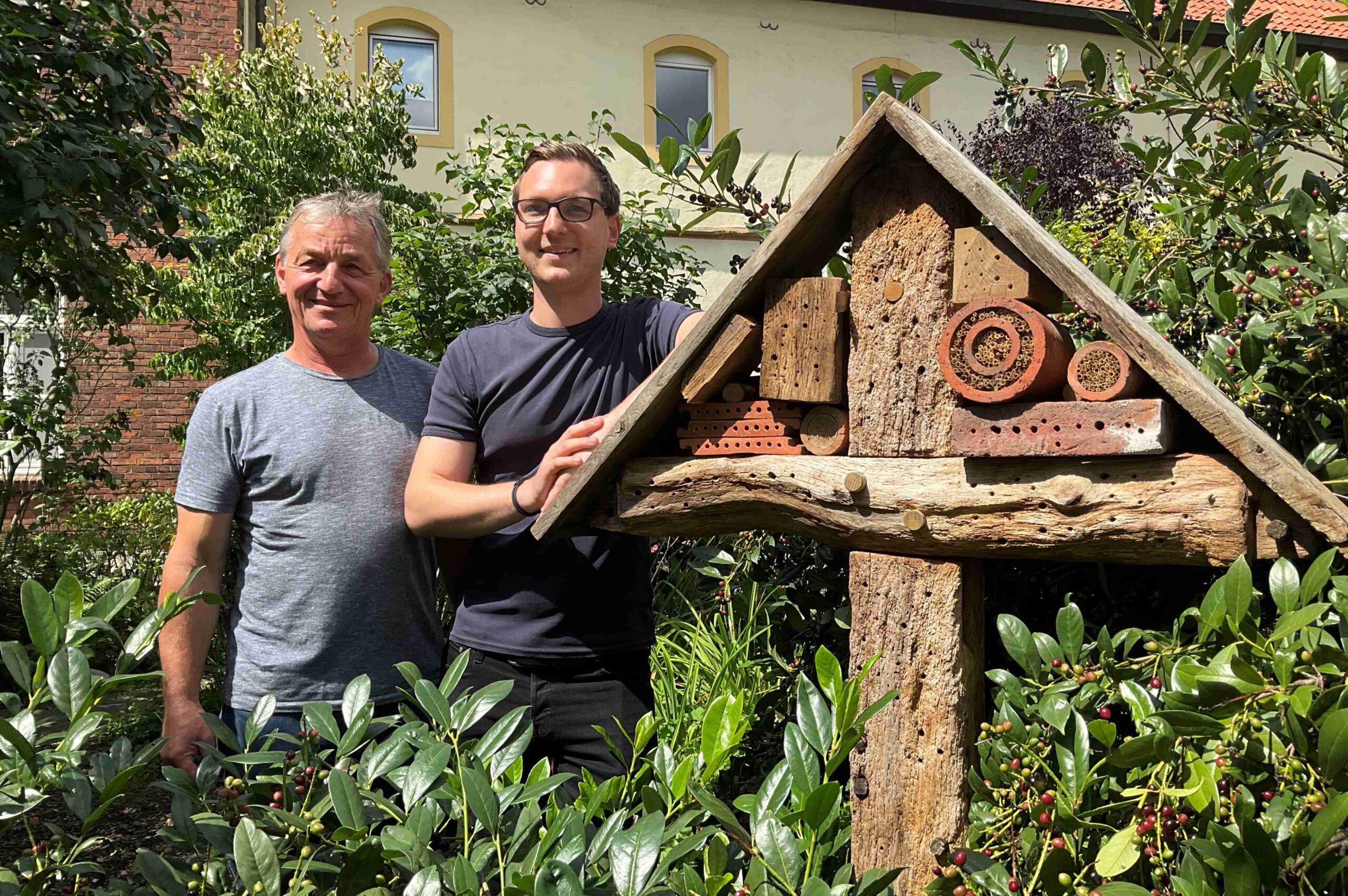 Volker und Felix Klosofski stehen neben bem selbstgebauten XXL-Insektenhotel im Klostergarten Wiedenbrück
