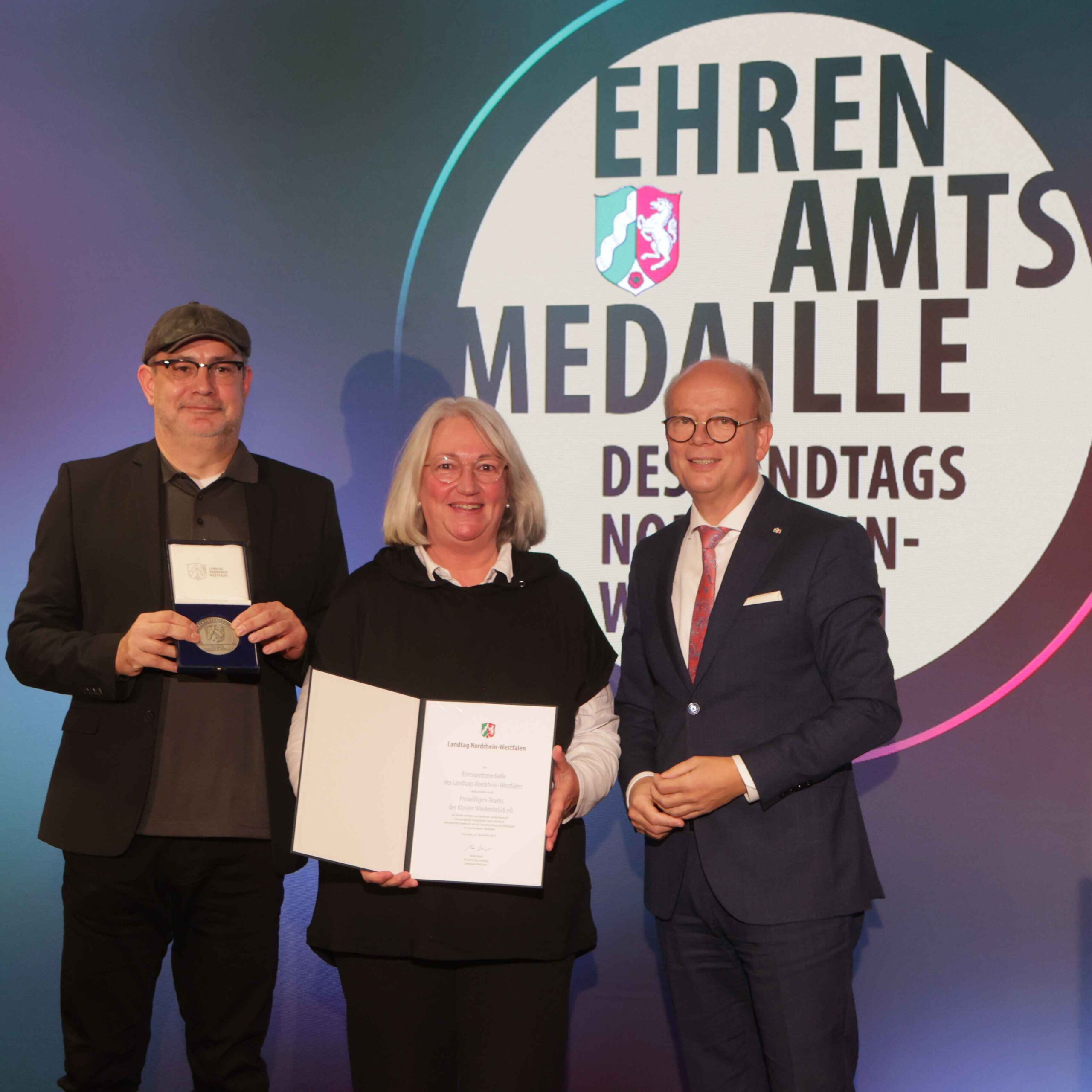 Michael Fiedler und Beate Kulak nehmen die Ehrenamtsmedaille von André Kuper entgegen.